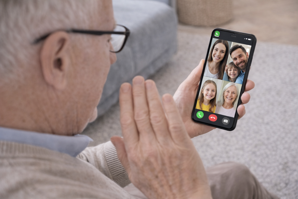 persona mayor haciendo una videollamada por whatsapp con su familia.
